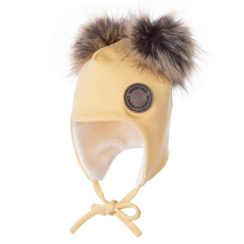 Gele babymuts van merinowol met pompons van imitatiebont.